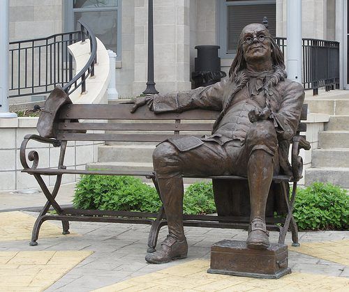 Outdoor bronze franklin sitting on a bench statue for the University