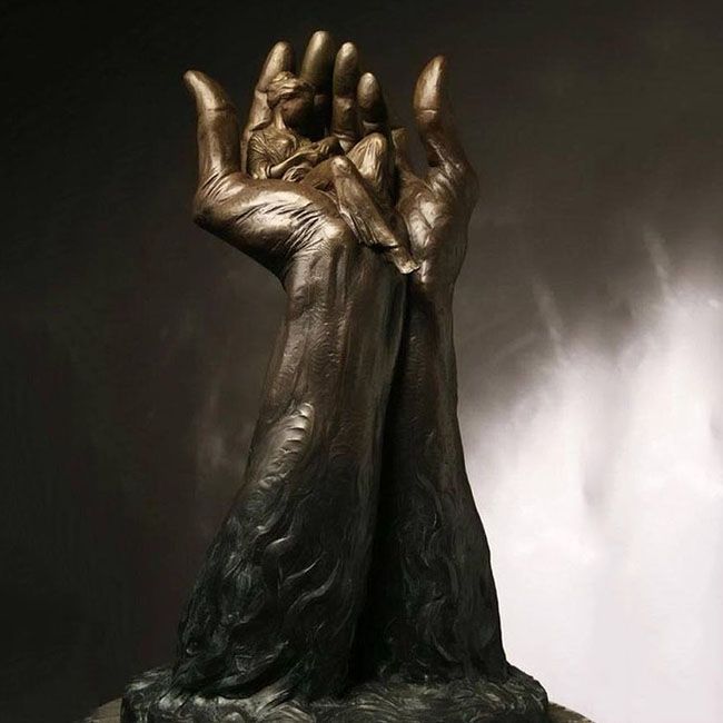 Bronze hand holding mother and child sculpture Agape by José Ismael Fernandez