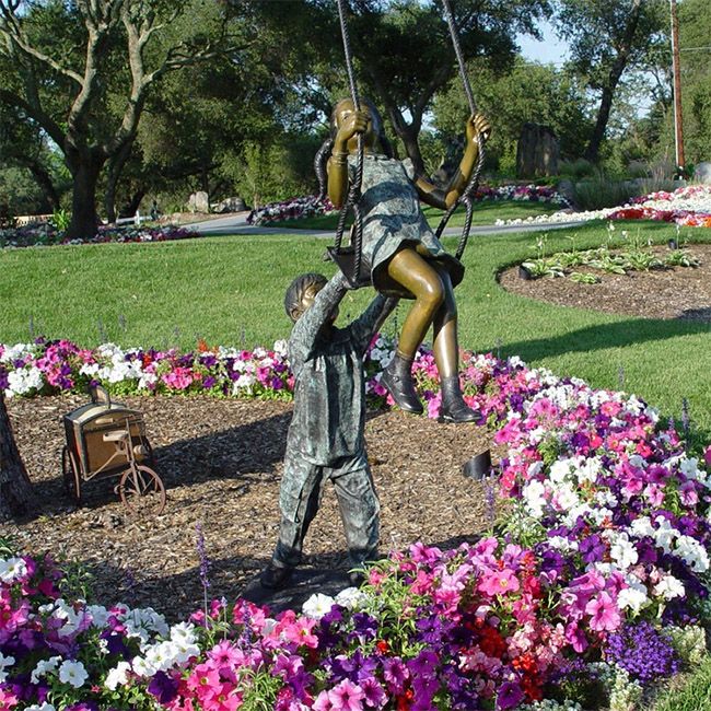 Boy and girl on swing garden statue