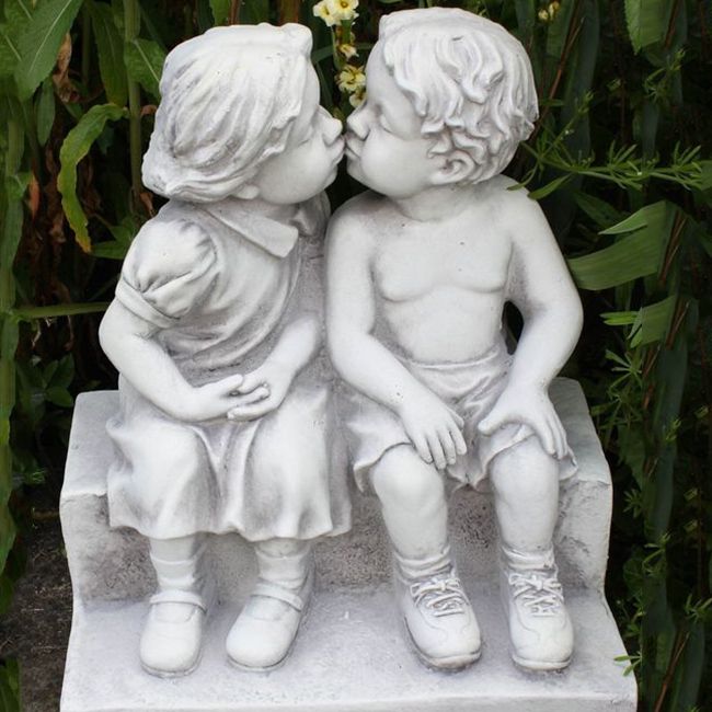 boy and girl sitting on a bench garden statue