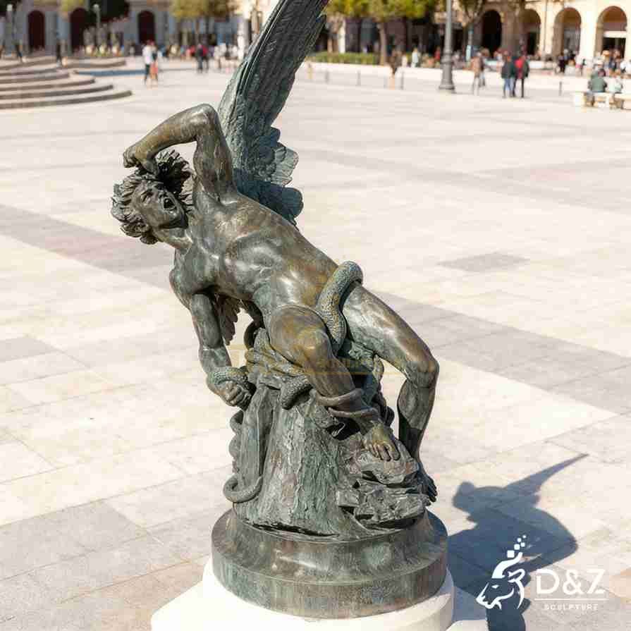 Bronze Fallen Angel Lucifer statue in a sorrowful crouching pose with dramatic wings in a public plaza