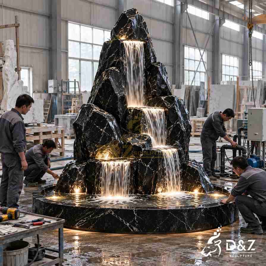 D&Z Sculpture workers assembling and testing a large black marble indoor waterfall fountain D&Z Sculpture workers assembling and testing a large black marble indoor waterfall fountain
