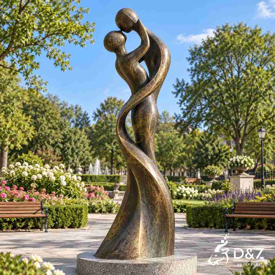 Abstract couple sculpture with two elongated bronze figures embracing in a flowing intertwined form outdoors Abstract couple sculpture with two elongated bronze figures embracing in a flowing intertwined form outdoors