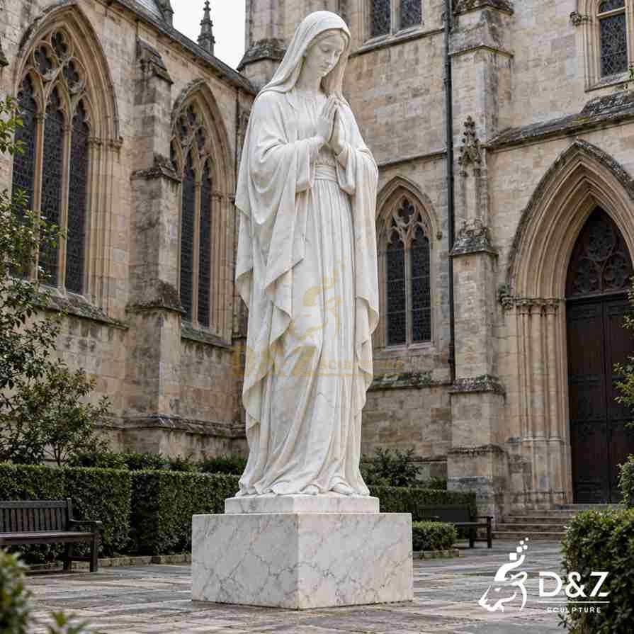 White marble Virgin Mary praying statue with hands joined in front of a Gothic church