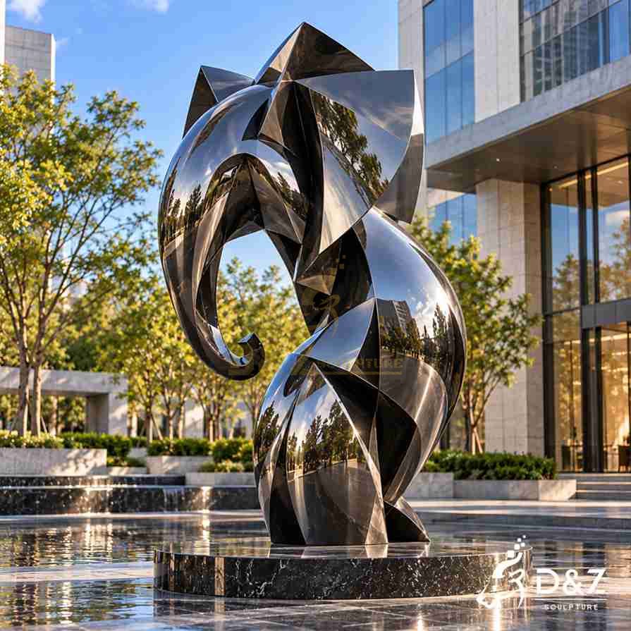 Modern abstract elephant sculpture with glossy reflective metal surfaces and a curled trunk outside a contemporary commercial building. Modern abstract elephant sculpture with glossy reflective metal surfaces and a curled trunk outside a contemporary commercial building.