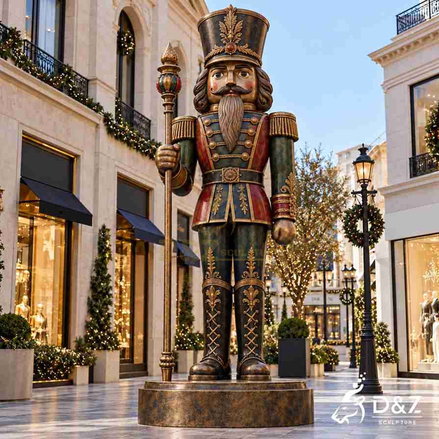 Large bronze nutcracker soldier statue holding an ornate staff, wearing a red and green military uniform in a Christmas shopping street. Large bronze nutcracker soldier statue holding an ornate staff, wearing a red and green military uniform in a Christmas shopping street.