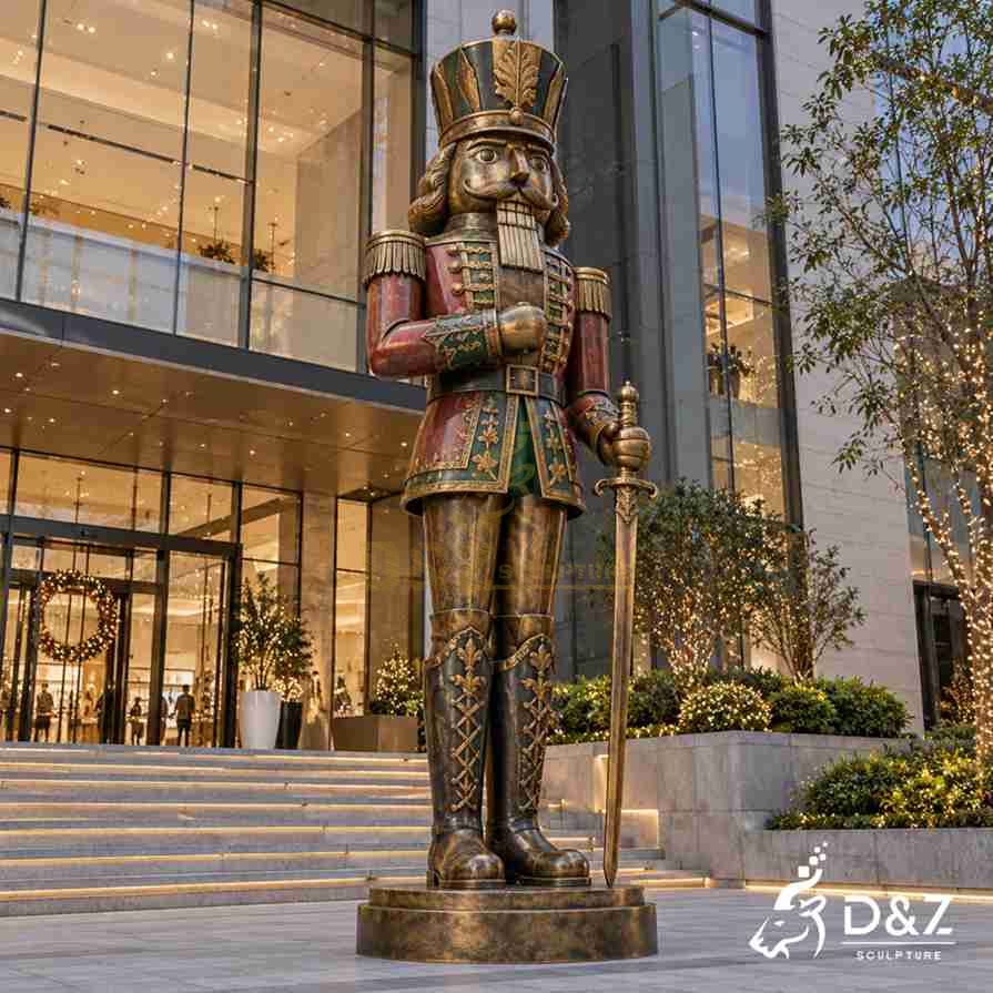Large outdoor bronze nutcracker soldier statue holding a ceremonial sword outside a modern commercial building decorated for Christmas. Large outdoor bronze nutcracker soldier statue holding a ceremonial sword outside a modern commercial building decorated for Christmas.