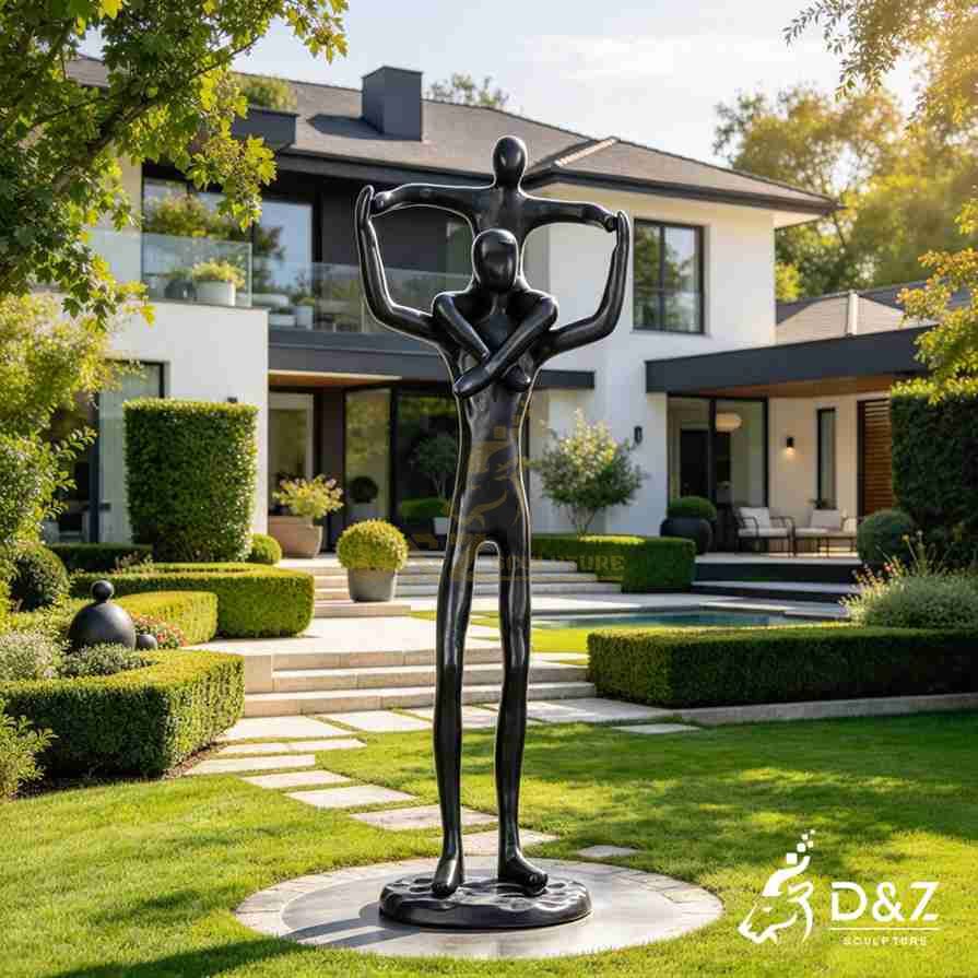 Black abstract sculpture of a father carrying his son on his shoulders in a landscaped courtyard. Black abstract sculpture of a father carrying his son on his shoulders in a landscaped courtyard.