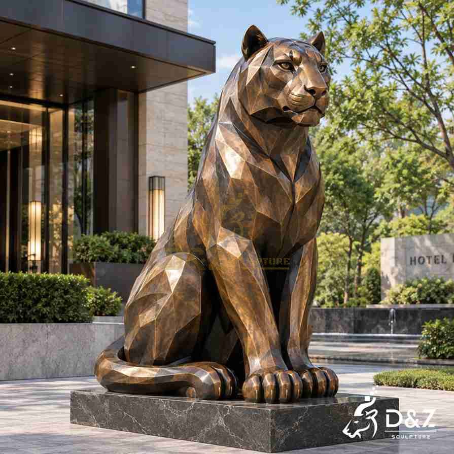 Three-quarter view of a bronze-finish sitting tiger statue with faceted shoulders and a curled tail at a hotel entrance. Three-quarter view of a bronze-finish sitting tiger statue with faceted shoulders and a curled tail at a hotel entrance.