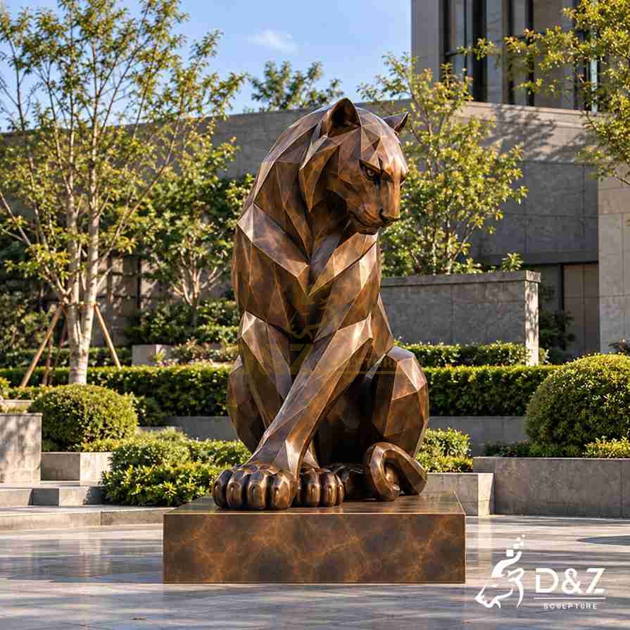Geometric sitting tiger statue with crossed front legs, a lowered head and a bronze finish in a landscaped courtyard. Geometric sitting tiger statue with crossed front legs, a lowered head and a bronze finish in a landscaped courtyard.