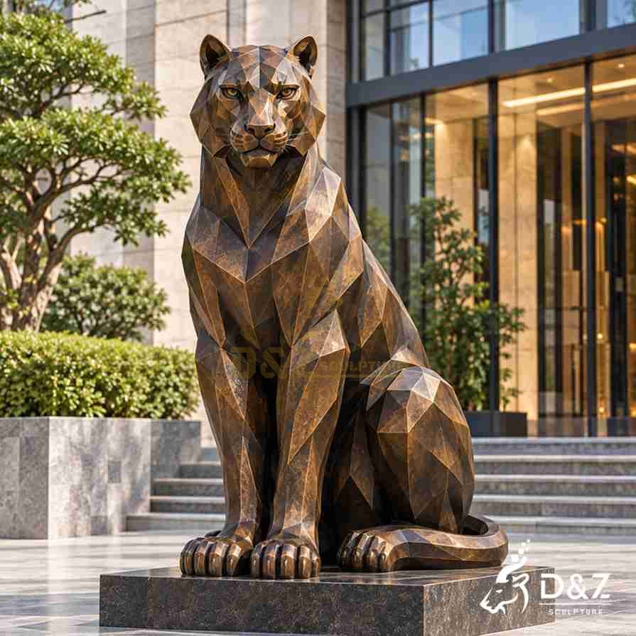 Front view of a geometric sitting tiger statue with upright forelegs and a curled tail on a dark base outside a hotel. Front view of a geometric sitting tiger statue with upright forelegs and a curled tail on a dark base outside a hotel.